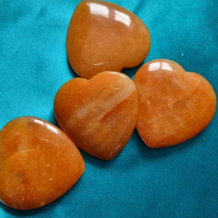 Four orange heart-shaped stones on a blue fabric background