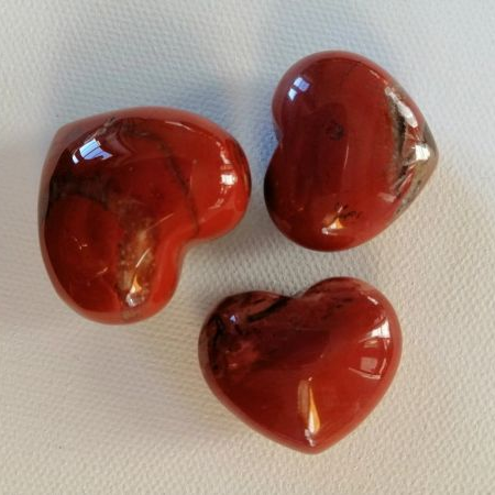 Three red heart-shaped stones on a light beige surface