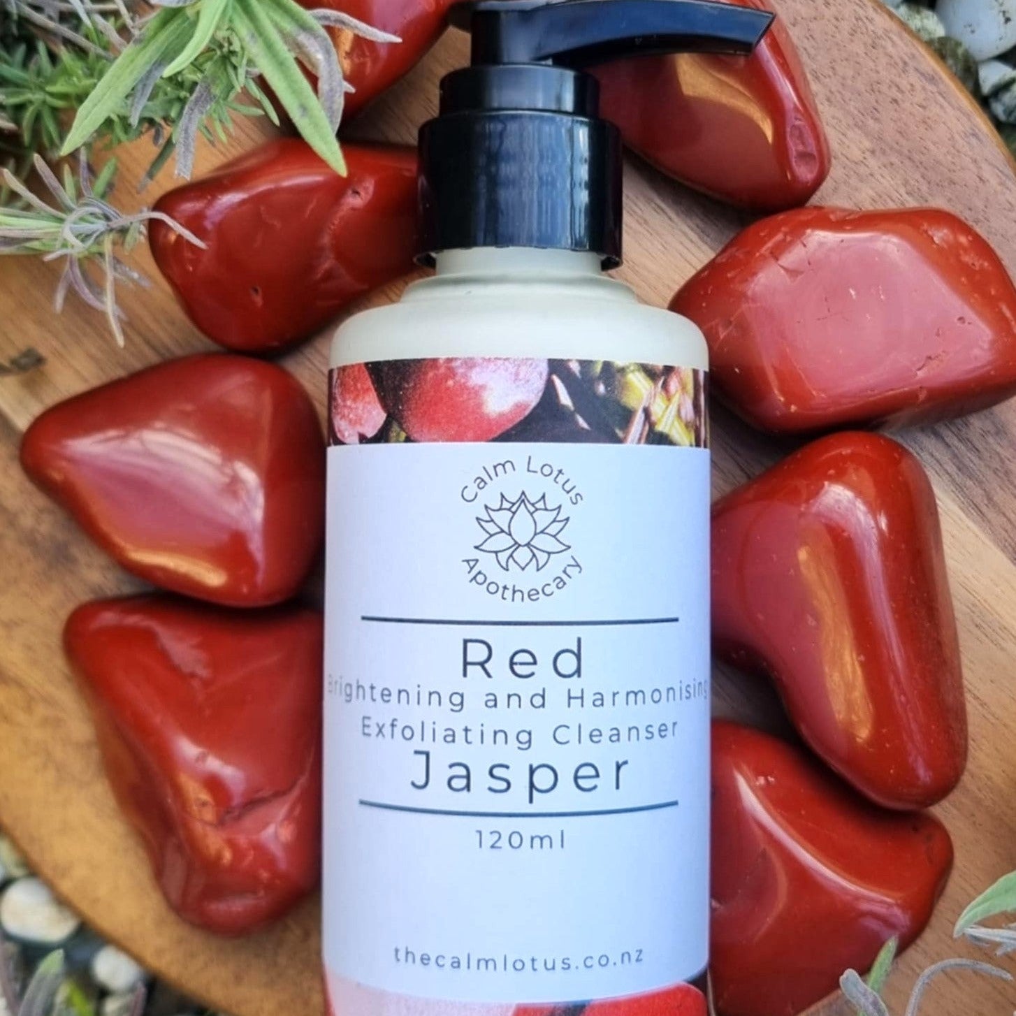 Bottle of 'Red Jasper' cleanser with natural elements on a wooden surface