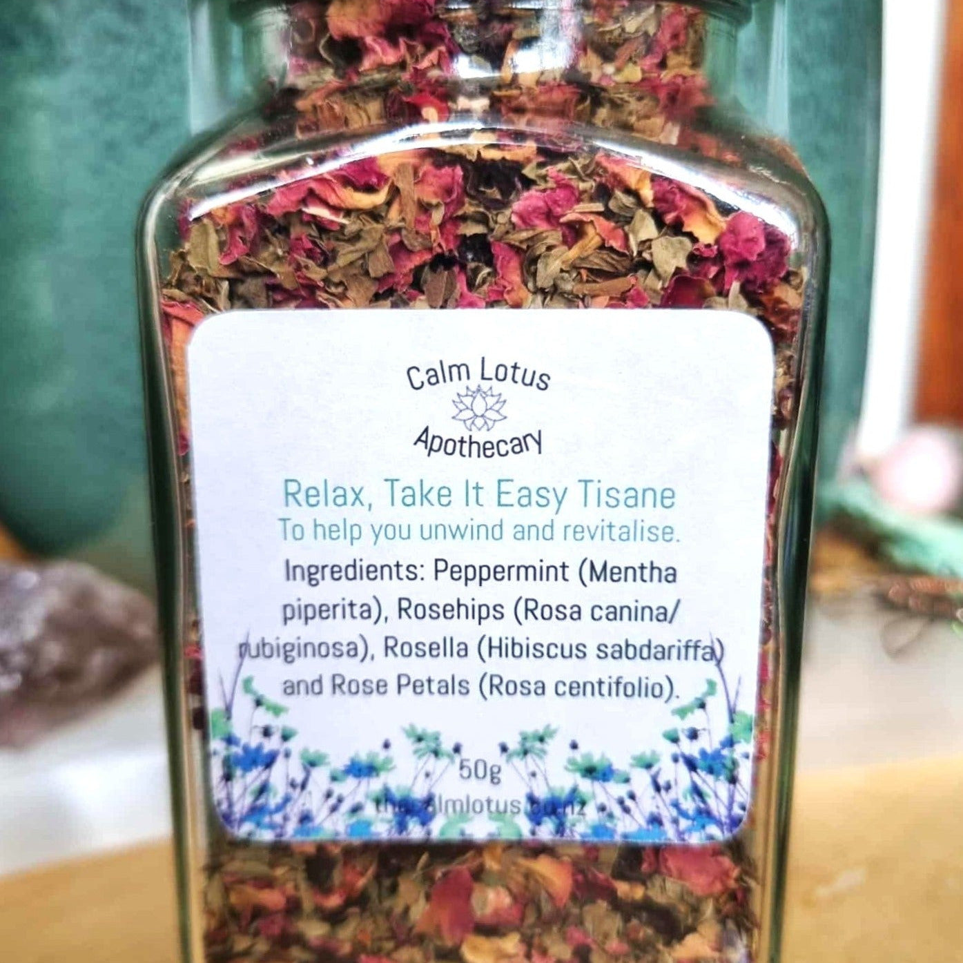 Jar of Calm Lotus Apothecary's 'Relax, Take It Easy Tisane' with a label on a wooden surface.