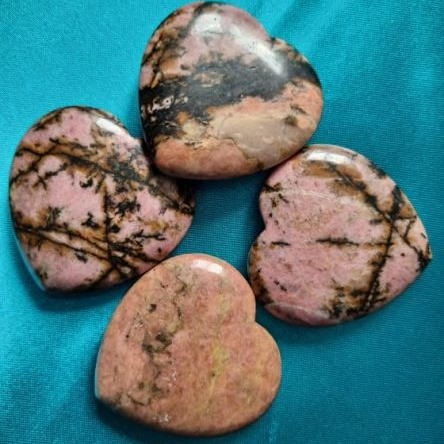 Four rhodonite stones on a turquoise fabric background