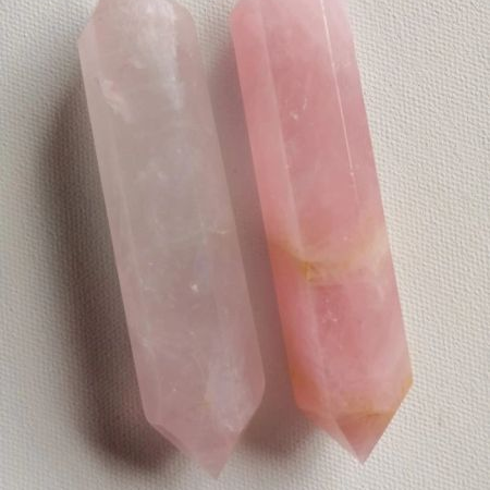 Two pink crystal wands on a light gray background