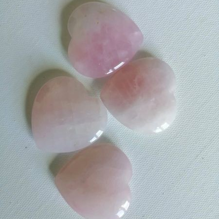 Four pink heart-shaped stones on a light gray background