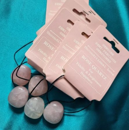 Set of rose quartz pendants with pink packaging on a blue background