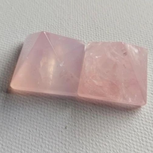 Pink pyramid shaped crystal on a textured gray surface