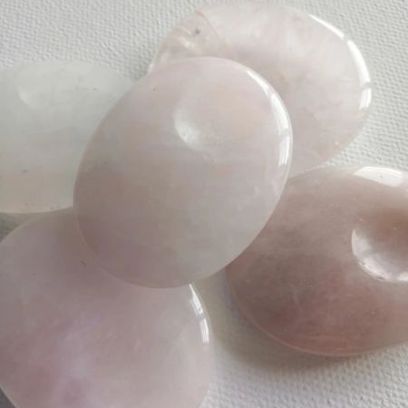 Rose quartz thumbstones on a white fabric background
