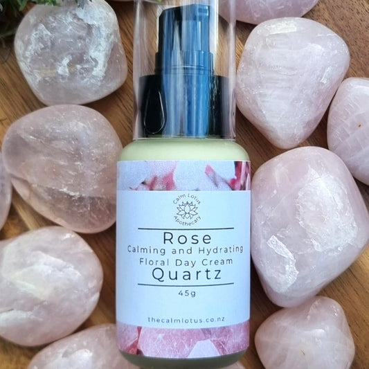 Rose quartz crystal with a bottle of floral day cream on a wooden surface