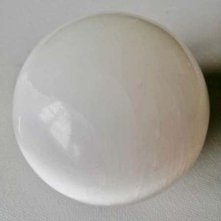 White spherical Selenite piece on a gray background