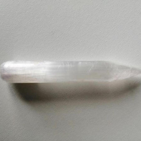 Selenite crystal wand on a light gray background