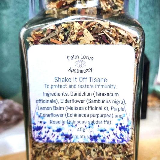 Jar of Calm Lotus Apothecary 'Shake It Off Tisane' with a label on a wooden surface.