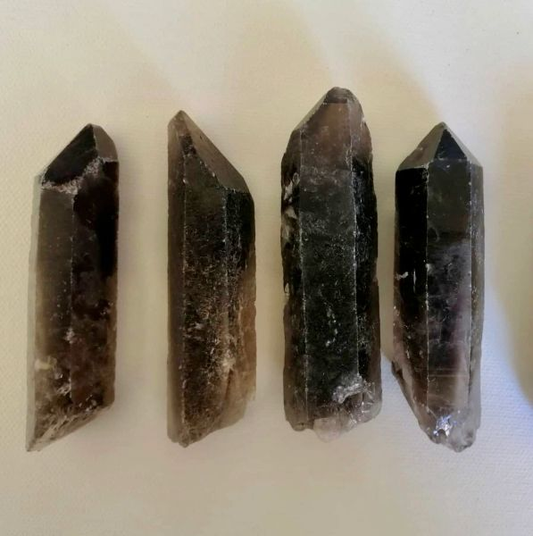 Four raw crystal points on a light beige background