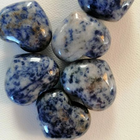 Blue and white speckled heart shaped stones on a white surface