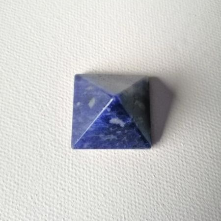 Pyramid shaped blue stone on a white textured background