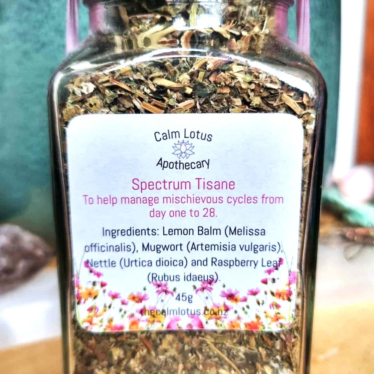 Jar of Calm Lotus Apothecary Spectrum Tisane with a label on a wooden surface.