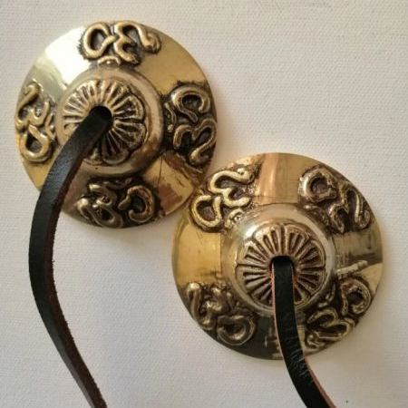 Bras cymbals with intricate designs on a white background