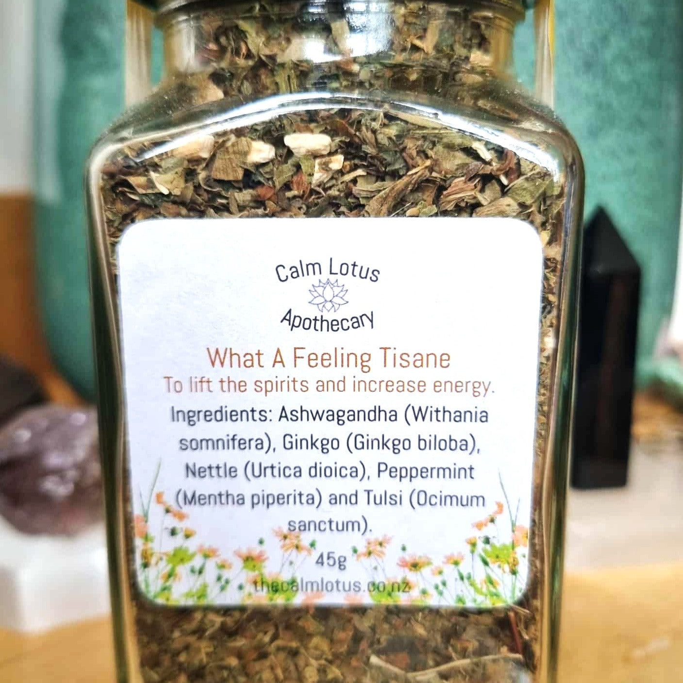 Jar of Calm Lotus Apothecary What A Feeling Tisane on a wooden surface with a blurred background.