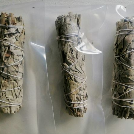Three bundles of sage wrapped in twine on a white background