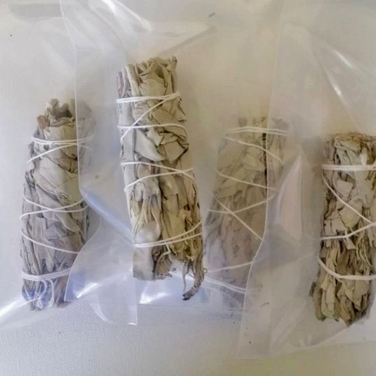 Four bundles of sage wrapped in twine on a white background